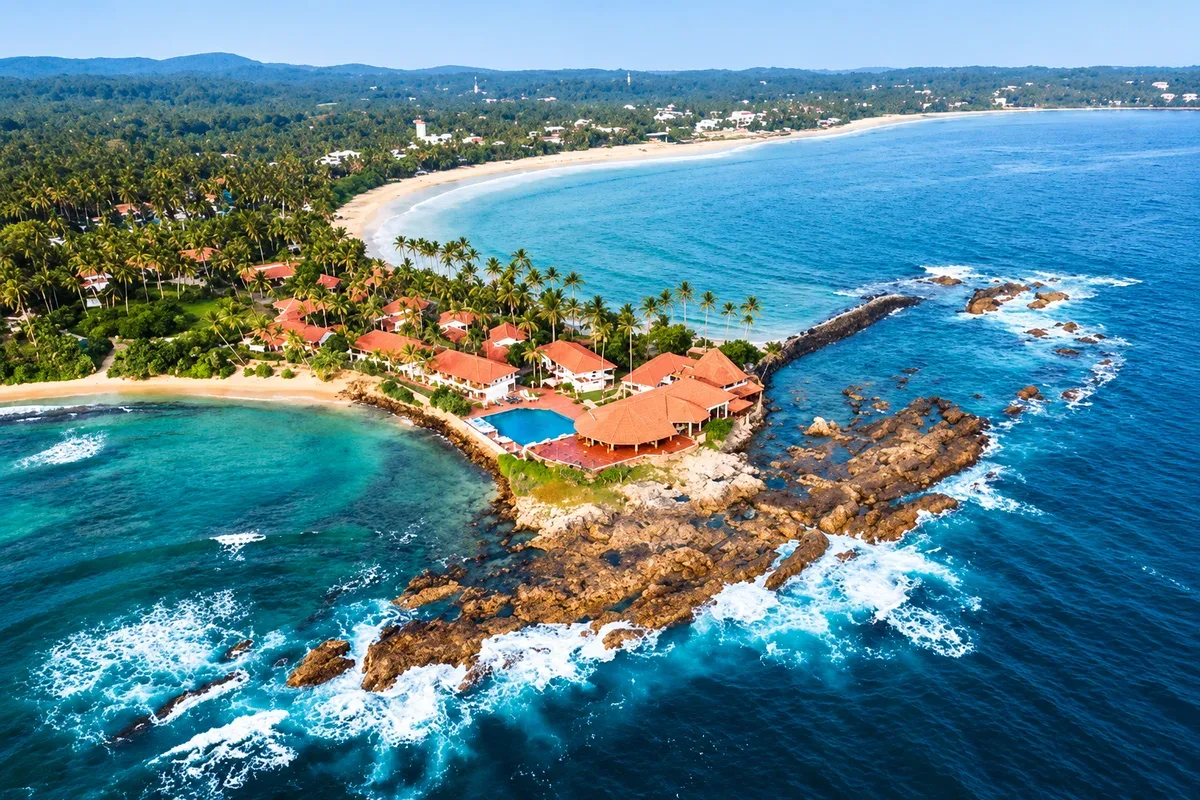Aerial view of a rocky headland with red-roofed buildings and sandy bays