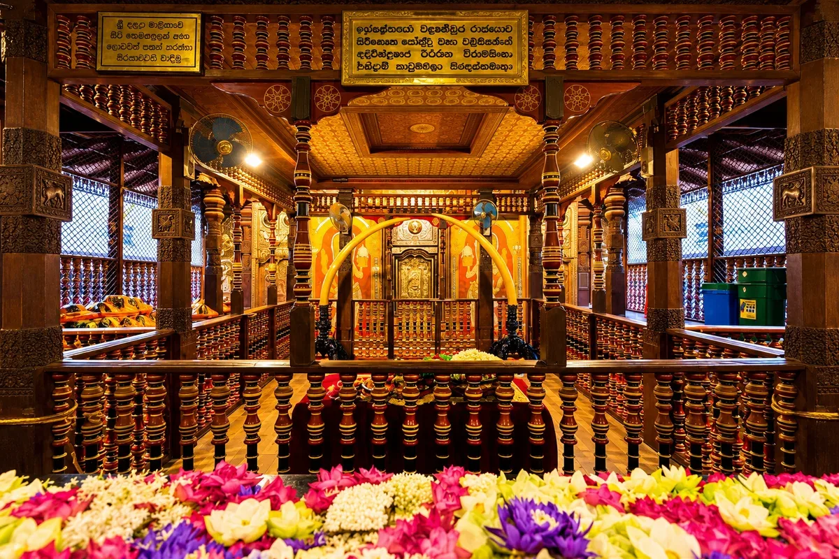 Flower offerings and carved wooden pillars inside a temple in Kandy