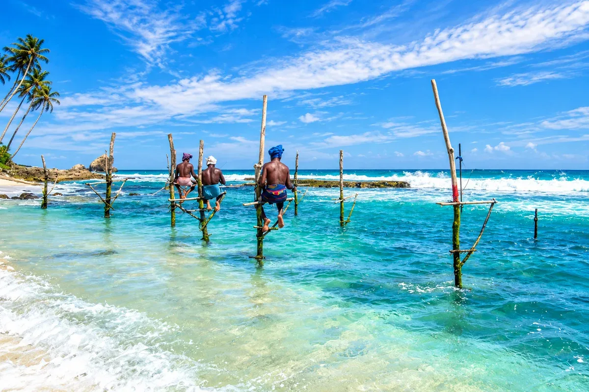 Fishermen sitting on wooden stilts above the coastal waves