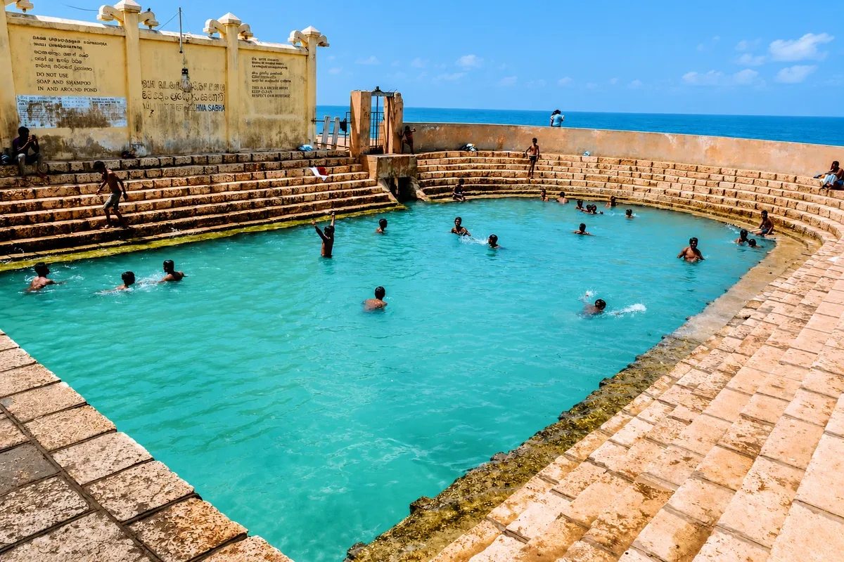 People swimming in a stone-sided bathing pool beside the sea