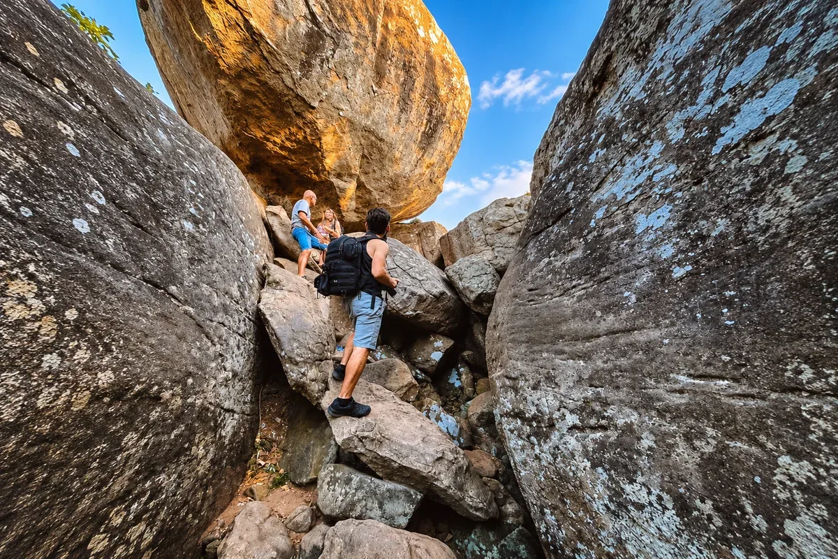 Hikers climbing through the large boulders on the way up Pidurangala